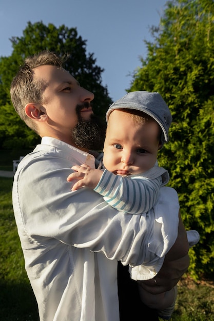 Photo father holding his son in his arms on a background of greenery