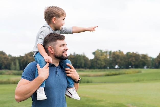 Photo father holding his son on his shoulders side view