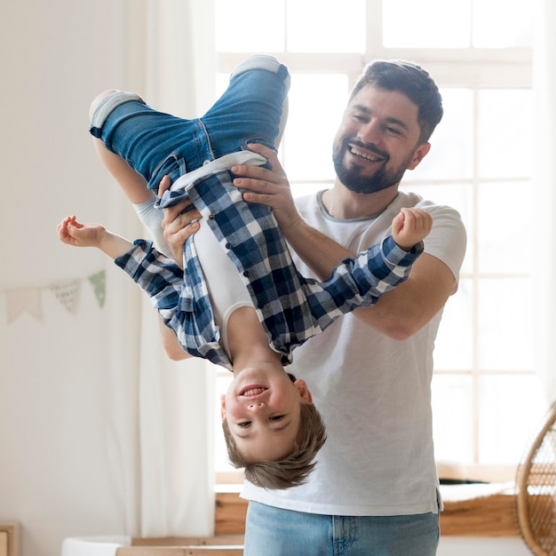 Photo father holding his son upside down