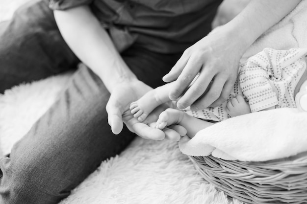 Father holding the legs of his newborn son closeup black and white photo