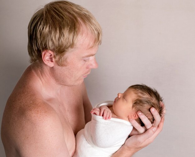 Father holding and looking on little sleeping baby