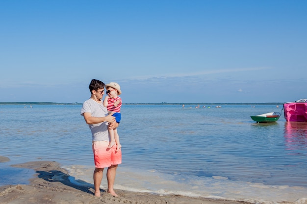 Padre che tiene il figlio sulle mani in spiaggia.