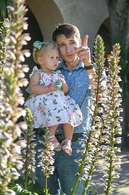 Father holds baby daughter in white dress and smiles father's day daddy's day sunny day