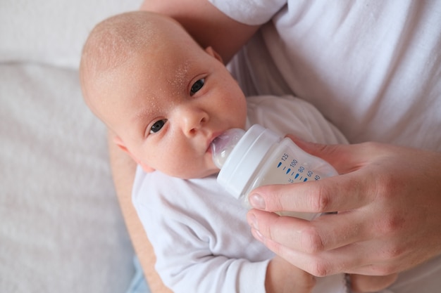 A father holds and bottle feeds his newborn baby.