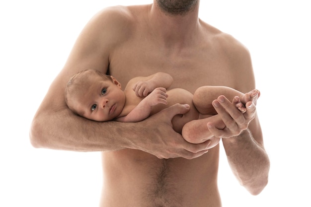 Father holds his naked newborn baby in the studio