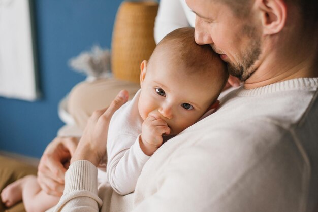 Foto un padre tiene il suo neonato tra le braccia un padre bacia il suo figlio piccolo