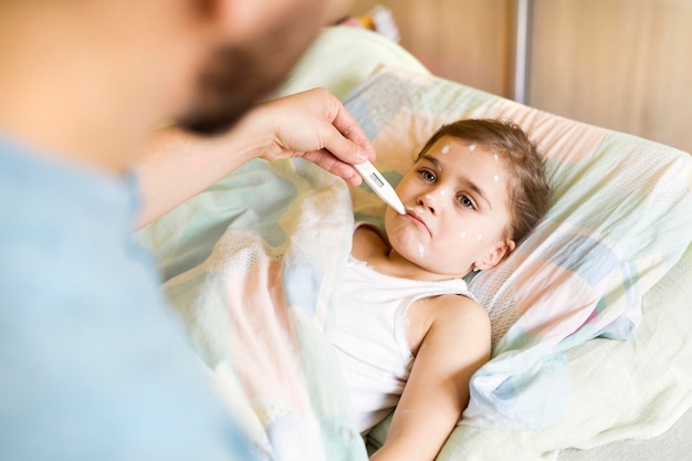 Father at home caring for daughter having chickenpox