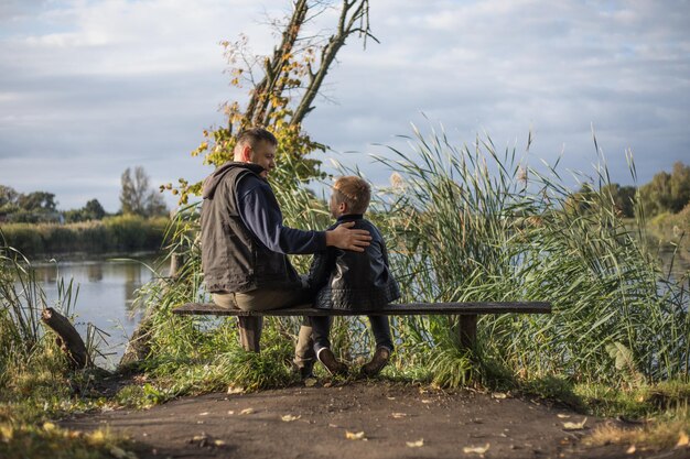 Father hugging his son outdoors on the bench Precious moments between Dad and son