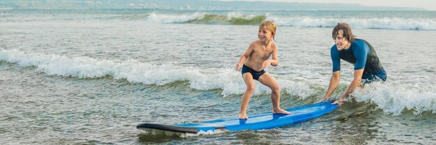 Father or instructor teaching his 4 year old son how to surf in the sea on vacation or holiday. Travel and sports with children concept. Surfing lesson for kids. BANNER, LONG FORMAT