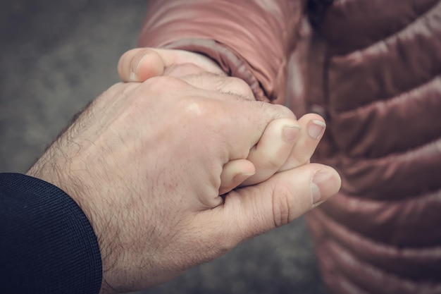 The father is holding his daughter's hand closeup shot