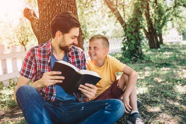 father is looking at his son and holding a book