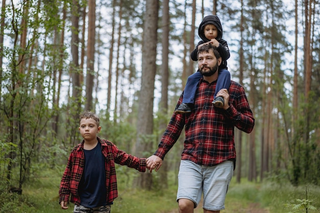 A father is walking down the lane in forest with two sons