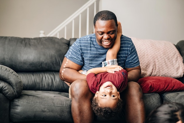 father and kids at home playing on couch african american or black father with his children enjoy