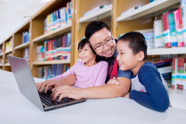 Father and kids learning online together in library Father talks to son