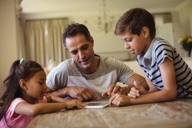 Father and kids using digital tablet in living room