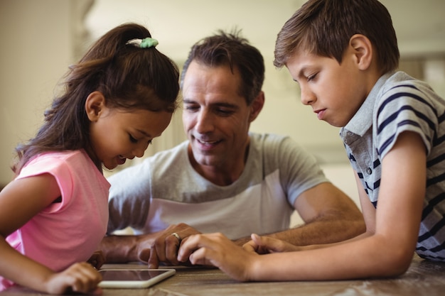 Photo father and kids using digital tablet in living room