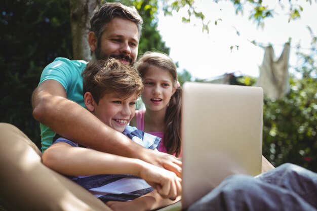 Father and kids using laptop in garden