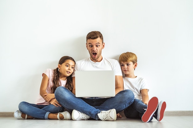 The father and kids with a laptop sitting on the floor