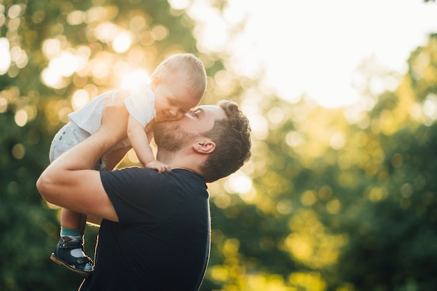 Photo father kissing his baby in the park
