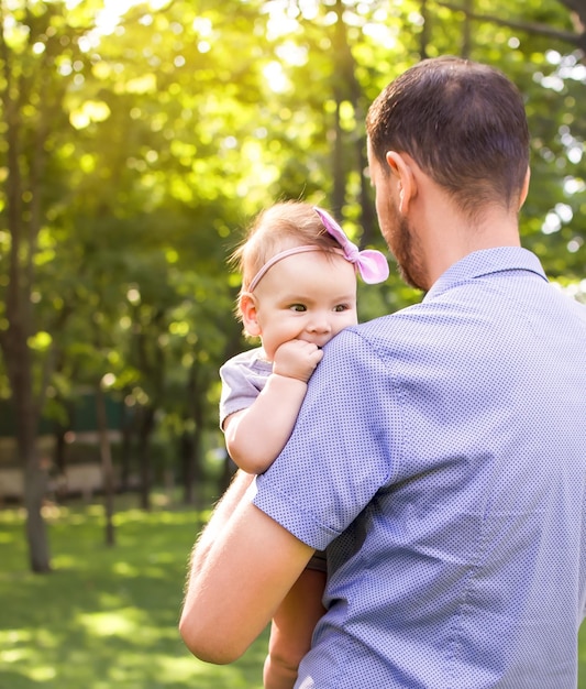 Father kissing little daughter while holding her in his arms in the park