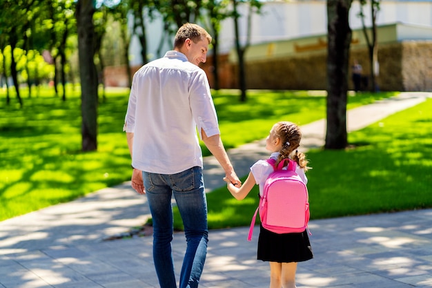 father leads daughter to school in first grade. first day at school. back to school.