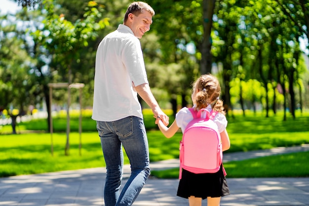 Father leads daughter to school in first grade