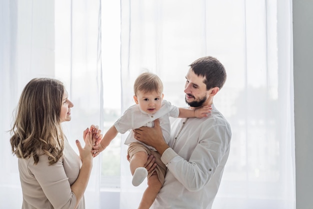 The father lifting baby boy on the air mother is watching smiling clapping cheering on the side