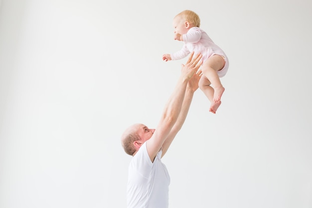 Father lifting baby girl. Happy father picks up and throws his lifting a small child. Home