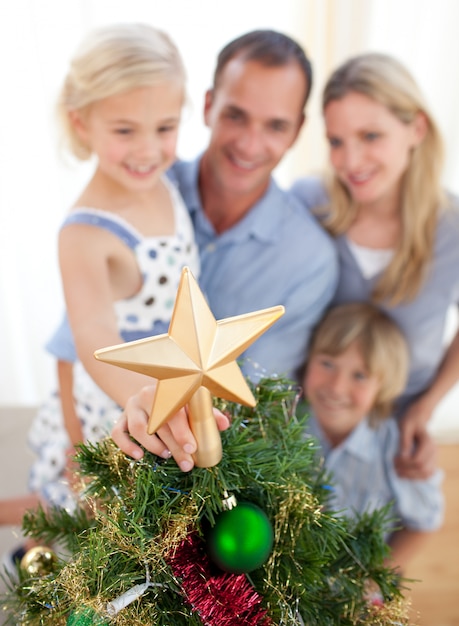 Foto padre che solleva sua figlia per mettere la stella di natale in cima all'albero