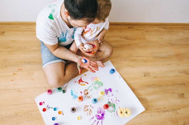 Father and little boy of fivr years having fun painting at home