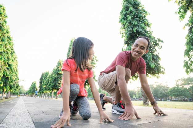 Father and little daughter do exercises in outdoor healthy lifestyle of family with child