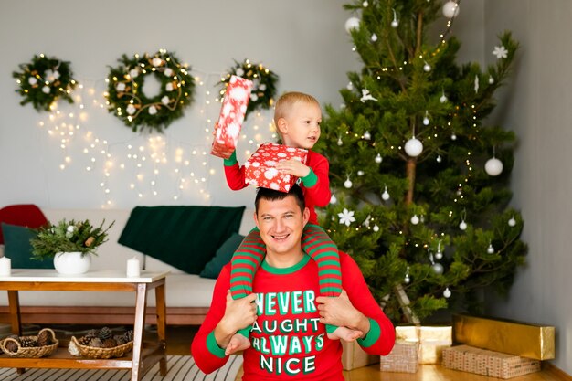 Father and little son in cozy pajamas unpacking gifts