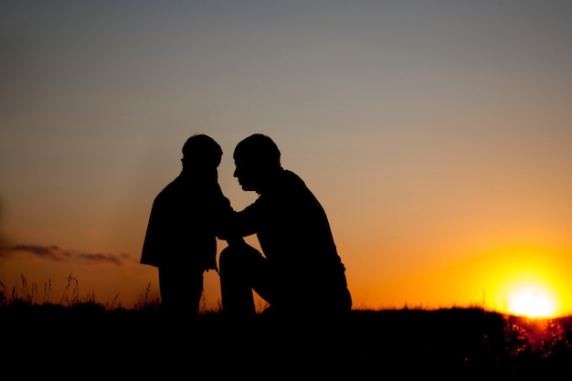 Father and little son - silhouettes at sunset