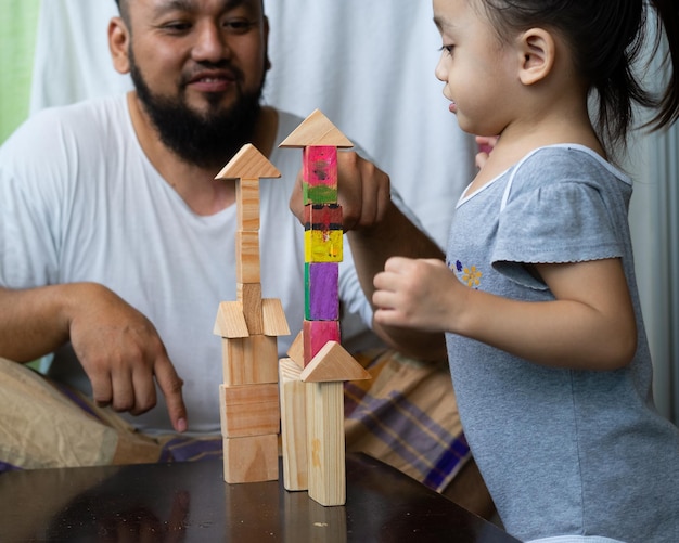 Father looking at daughter stacking toy blocks