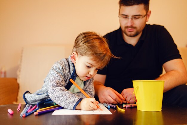 Photo father looking at son making drawing on table at home