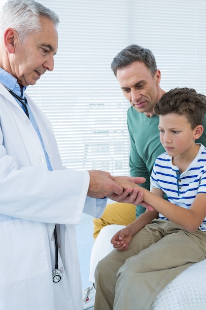 Father looking at sons hand while being examined by doctor