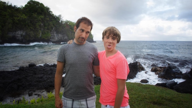 Foto padre che guarda verso figlio che fa faccia contro il mare