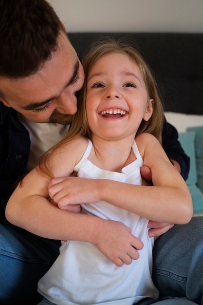 Photo father making his daughter laugh by tickling her