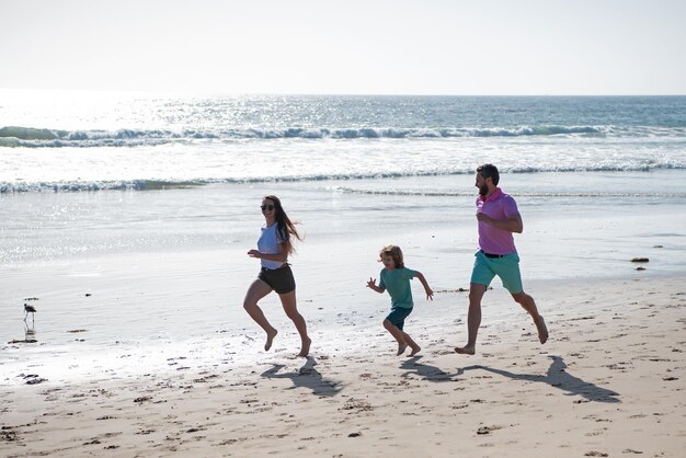 Foto padre, madre e figlio corrono sulla spiaggia concetto di stile di vita familiare sano vacanze estive in mare stile di vita sano