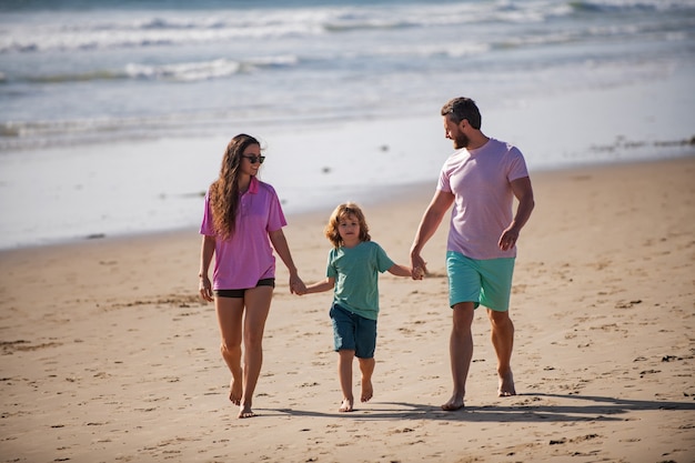 Father mother and child son holding hands and walking on beach