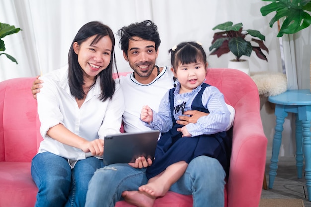 Famiglia asiatica della figlia della madre del padre famiglia giovane e attraente felice che guarda la compressa