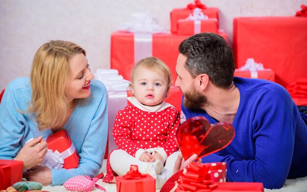 父、母、そして娘の子供。彼らの心に愛を保ちます。バレンタイン・デー。赤いボックス。プレゼントボックスで幸せな家族。家族への愛と信頼。小さな女の子とひげを生やした男と女。