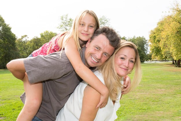 Father and mother giving piggyback ride to the daughter