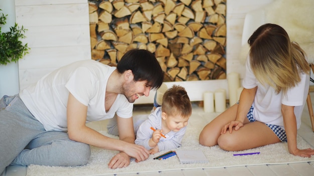 Отец и мать помогают своему ребенку рисовать в гостиной