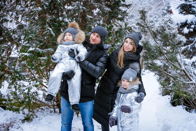Father and mother hold children in their arms laughing cheerfully family winter walk in forest raisi...