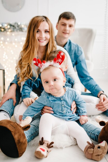 Il padre, la madre tiene il piccolo figlio e la figlia vicino all'albero di natale. felice anno nuovo e buon natale. interno decorato di natale. il concetto di vacanza in famiglia. avvicinamento.