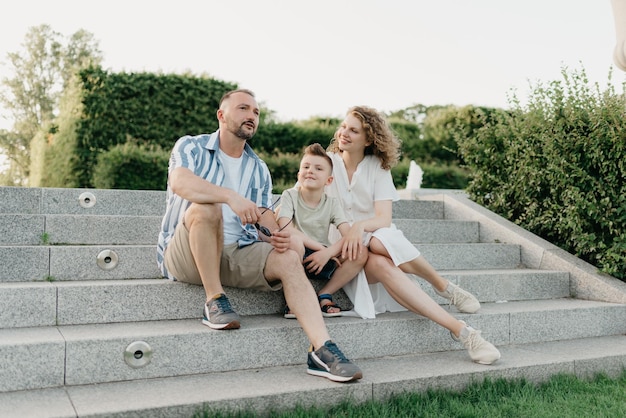 Father mother and son are sitting on the steps in the garden of an old town