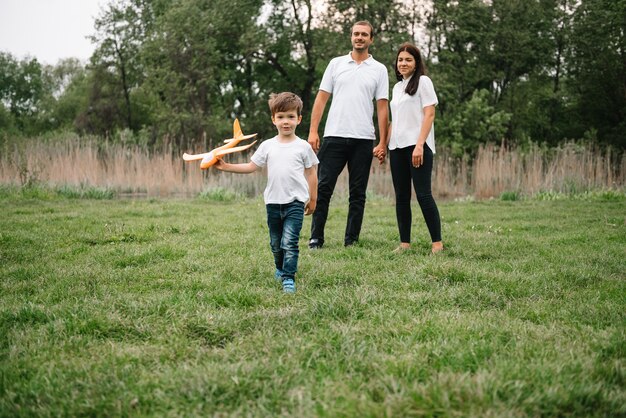 Photo father, mother and son playing with toy airplane in the park. friendly family