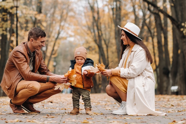 Padre e madre con figlio che camminano nel parco autunnale