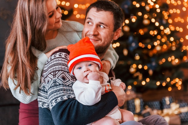 Father and mother with their child together in christmas decorated room.